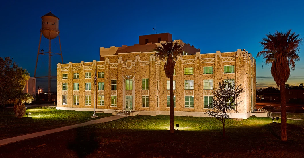 La Salle County Courthouse illuminated at dusk, with the Cotulla water tower