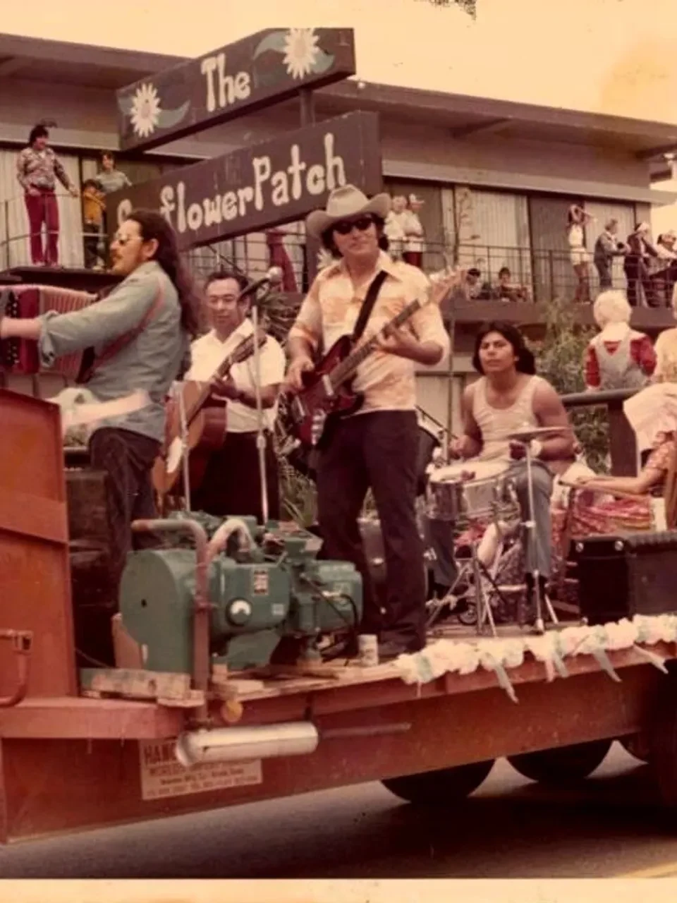 Archival photograph of musicians playing accordion, guitar, and drums on a decorated parade float