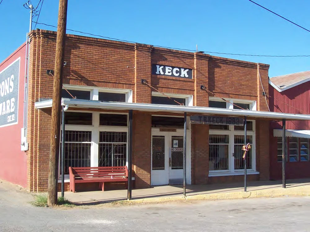 T. R. Keck and Sons brick storefront, covered sidewalk, and bench in Cotulla in 2011